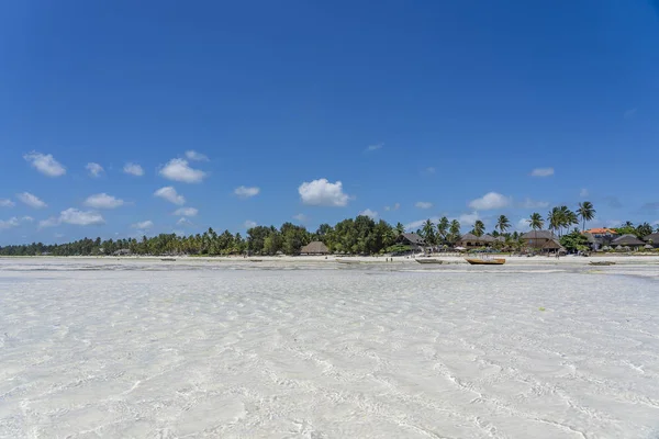 Playa tropical con aguas cristalinas, cielo azul y palmeras verdes en la isla Zanzíbar, Tanzania, África Oriental — Foto de Stock