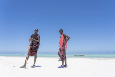 Afrikalı erkekler geleneksel kıyafetler giyip okyanusun kenarında, kumsalda, Zanzibar, Tanzanya 'da dururlar.