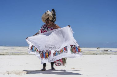 Afrikalı kadın, Doğu Afrika 'daki Tanzanya' daki Zanzibar adasındaki kumsalda okyanus kenarında turistler için hediyelik eşya ve giysi satıyor.