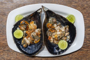 Büyük bir deniz kabuğundaki çiğ istiridye eti, Doğu Afrika 'daki Zanzibar adasındaki yerel bir restoranda yemek için servis ediliyor.