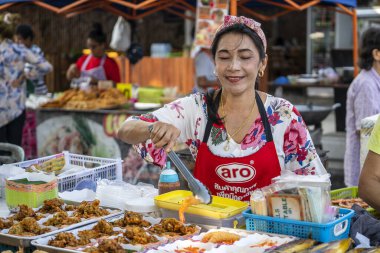 Thai street vendor woman prepares and sells food on the traditional street market at island Koh Phangan, Thailand