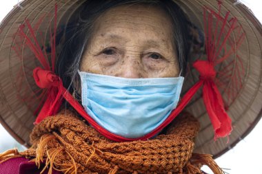 Sapa, Vietnam - march 02, 2020 : Ethnic Hmong old woman with protective mask on the face on a street of Sapa, North Vietnam