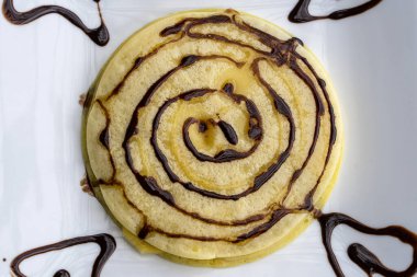 Çikolata soslu krepler beyaz tabakta, yakın çekim, üst manzara.