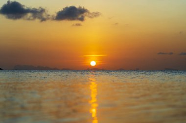 Tayland 'daki Koh Phangan adasında deniz suyunun üzerinde güzel bir günbatımı. Seyahat ve doğa kavramı. Akşam gökyüzü, bulutlar, güneş ve deniz suyu