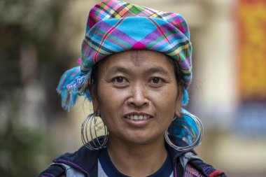 Sapa, Vietnam - Mart 04, 2020: Geleneksel kıyafet ve mücevher giyen etnik Hmong kadını turistlerin Sapa, Kuzey Vietnam 'daki dağ köyünde el sanatları satmalarını bekliyor