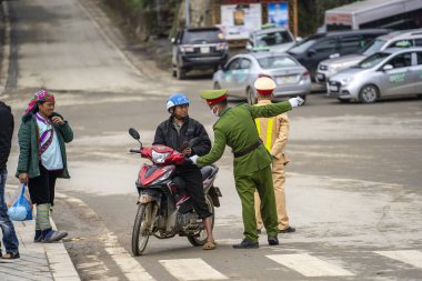 Sapa, Vietnam - Mart 04, 2020: Vietnamlı polis memuru Kuzey Vietnam 'daki Sapa dağ köyünde trafik kurallarını ihlal ettiği için bir motosiklet sürücüsünü durdurdu