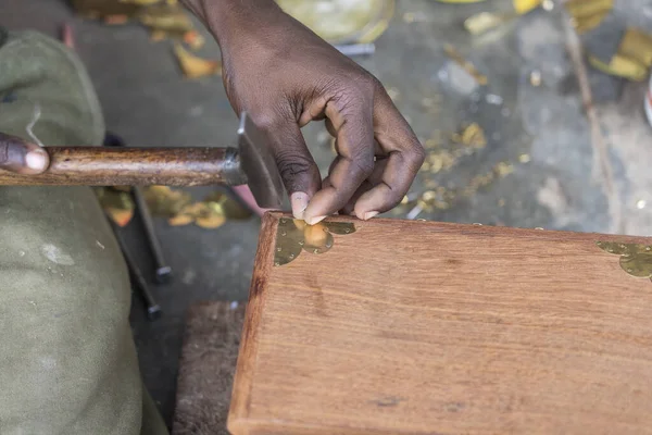 African man hammer a nail into a wooden box on the street on the island of Zanzibar, Tanzania, East Africa, close up