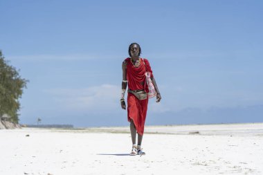 Zanzibar, Tanzanya - 28 Ekim 2019: Geleneksel giysiler giymiş Afrikalı adam kumsalda okyanus kenarında duruyor, Zanzibar, Tanzanya