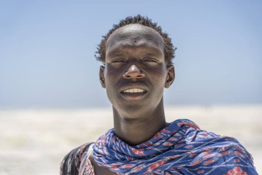 Zanzibar, Tanzanya - 28 Ekim 2019: Geleneksel giysiler giymiş Afrikalı adam kumsalda okyanus kenarında duruyor, Zanzibar, Tanzanya