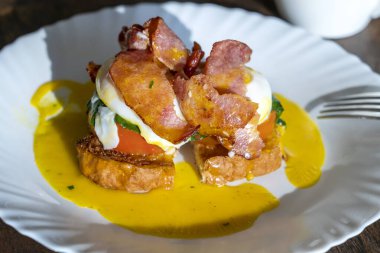 Pastırmalı Benedict usulü yumurta, kızarmış ekmek ve domates. Kahvaltıda haşlanmış yumurtalı sandviç.