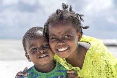 Zanzibar, Tanzanya - 12 Aralık 2019: Genç mutlu Afrikalı kız ve oğlan Doğu Afrika 'daki Tanzanya' nın Zanzibar adasındaki tropik plajda deniz suyu yakınında.