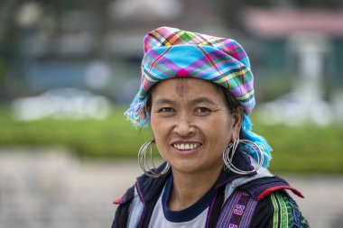 Sapa, Vietnam - Mart 04, 2020: Geleneksel kıyafet ve mücevher giyen etnik Hmong kadını turistlerin Sapa, Kuzey Vietnam 'daki dağ köyünde el sanatları satmalarını bekliyor