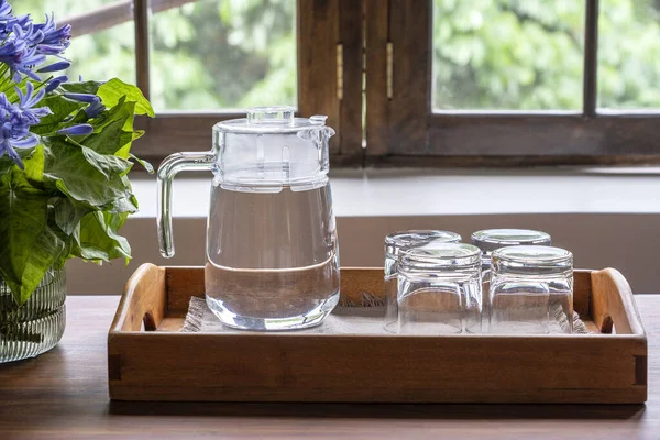 Una Jarra Agua Cuatro Vasos Vacíos Una Bandeja Madera Junto — Foto de Stock