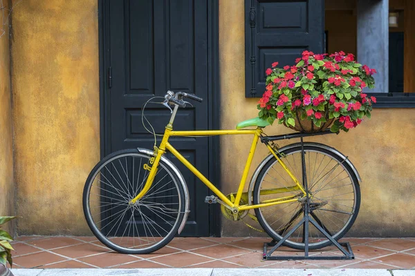 Gelbes Oldtimer Fahrrad Mit Korb Voller Roter Blumen Neben Einem — Stockfoto