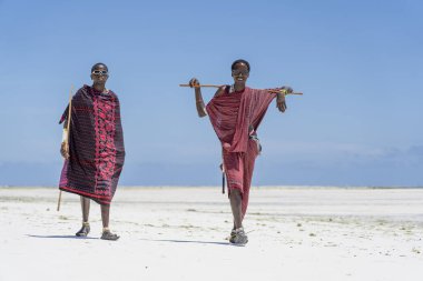 Zanzibar, Tanzanya - 28 Ekim 2019: Geleneksel giysiler giymiş iki Afrikalı adam okyanusun kıyısında, Tanzanya 'nın Zanzibar sahilinde duruyor.