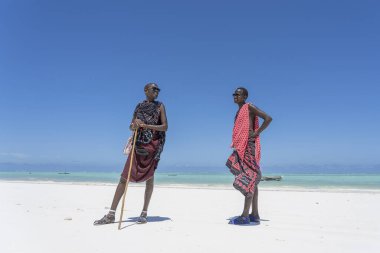 Zanzibar, Tanzanya - 28 Ekim 2019: Geleneksel giysiler giymiş iki Afrikalı adam okyanusun kıyısında, Tanzanya 'nın Zanzibar sahilinde duruyor.