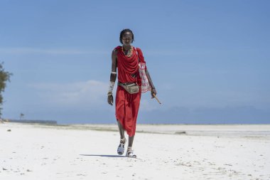 Zanzibar, Tanzanya - 28 Ekim 2019: Geleneksel giysiler giymiş Afrikalı adam kumsalda okyanus kenarında duruyor, Zanzibar, Tanzanya