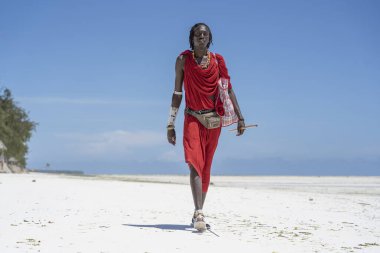 Zanzibar, Tanzanya - 28 Ekim 2019: Geleneksel giysiler giymiş Afrikalı adam kumsalda okyanus kenarında duruyor, Zanzibar, Tanzanya