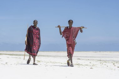 Zanzibar, Tanzanya - 28 Ekim 2019: Geleneksel giysiler giymiş iki Afrikalı adam okyanusun kıyısında, Tanzanya 'nın Zanzibar sahilinde duruyor.