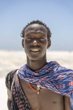 Zanzibar, Tanzanya - 28 Ekim 2019: Geleneksel giysiler giymiş Afrikalı adam kumsalda okyanus kenarında duruyor, Zanzibar, Tanzanya