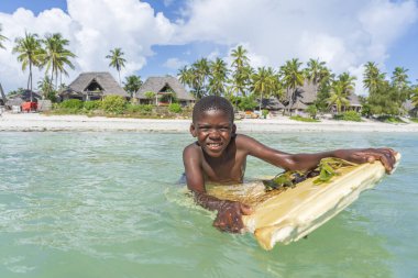 Zanzibar, Tanzanya - Aralık 01, 2019: Mutlu Afrikalı çocuk, Tanzanya 'nın doğusundaki Zanzibar adasındaki tropik plaj yakınlarında deniz suyunda yüzüyor.
