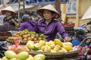Hanoi, Vietnam - Mart 01, 2020: Kadınlar Hanoi, Vietnam 'daki eski bir kasabanın sokak gıda pazarında meyve ve sebze satıyorlar