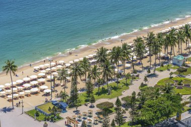 Nha Trang, Vietnam - 26 Mart 2020: Vietnam 'ın Nha Trang tatil beldesinde deniz suyu ve hindistan cevizi palmiye ağaçlarıyla dolu kumlu bir sahil manzarası