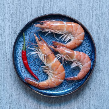 Kırmızı kırmızı biberli haşlanmış karides mavi tabakta arka planda, yakın plan, üst manzara