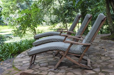 Göl kenarındaki tropikal bahçe terasında üç rahat güneş pansiyonu. Tanzanya, Doğu Afrika, yaklaşın.