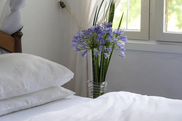 在房间里舒适的柔软的床和一束鲜花靠近窗户 坦桑尼亚 关门了 — 图库照片