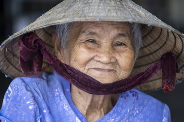 Nha Trang, Vietnam - 30 Mart 2020: Nha Trang, Vietnam 'da bir sokak pazarında yüzünde gülümseme olan etnik yaşlı kadın