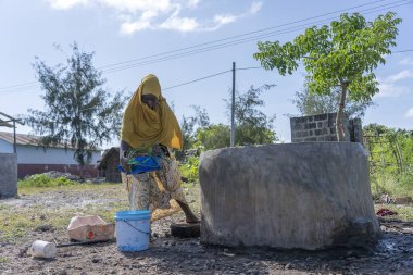 Zanzibar, Tanzanya - 14 Ocak 2020: Tanzanya, Doğu Afrika 'daki Zanzibar Adası' nda bir sokakta tanımlanamayan Afrikalı kız ve kova