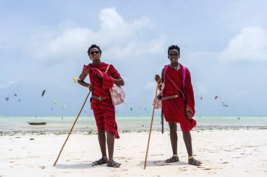 Zanzibar, Tanzanya - 15 Ocak 2020: Geleneksel kıyafetler giymiş iki Afrikalı adam okyanus kenarında, Tanzanya, Doğu Afrika 'daki Zanzibar adasının kumsalında duruyor.