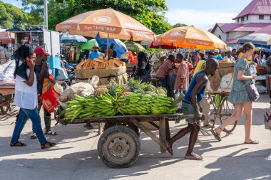Zanzibar, Tanzanya - 14 Kasım 2019: Afrikalı bir adam Doğu Afrika 'daki Tanzanya' nın Zanzibar adasındaki yerel bir sokak gıda pazarında tropikal meyve arabası taşıyor
