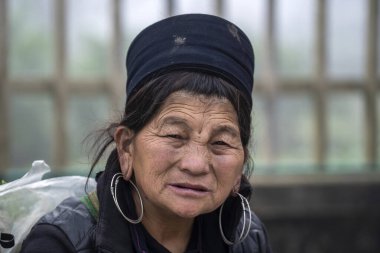 Sapa, Vietnam - Mart 06, 2020: Geleneksel kıyafet ve mücevher giyen etnik Hmong kadını turistlerin Sapa, Kuzey Vietnam 'daki dağ köyünde el sanatları satmalarını bekliyor