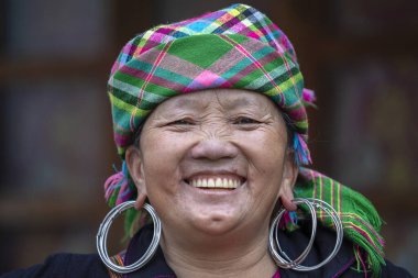 Sapa, Vietnam - Mart 06, 2020: Geleneksel kıyafet ve mücevher giyen etnik Hmong kadını turistlerin Sapa, Kuzey Vietnam 'daki dağ köyünde el sanatları satmalarını bekliyor