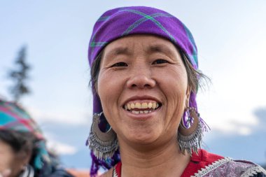 Sapa, Vietnam - Mart 06, 2020: Geleneksel kıyafet ve mücevher giyen etnik Hmong kadını turistlerin Sapa, Kuzey Vietnam 'daki dağ köyünde el sanatları satmalarını bekliyor