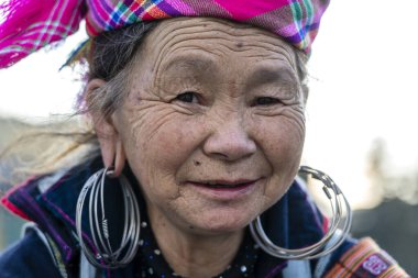 Sapa, Vietnam - Mart 06, 2020: Geleneksel kıyafet ve mücevher giyen etnik Hmong kadını turistlerin Sapa, Kuzey Vietnam 'daki dağ köyünde el sanatları satmalarını bekliyor