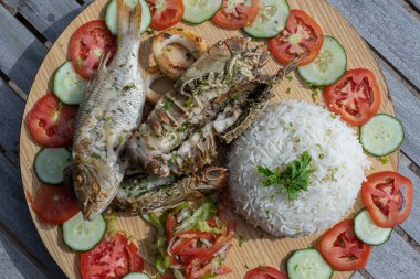 Deniz ürünleri ve sebzeli beyaz pirinç, yakın çekim. Doğu Afrika 'nın Zanzibar adasındaki restoranda balık, mürekkep balığı, karides, pirinç, domates ve salatalık.