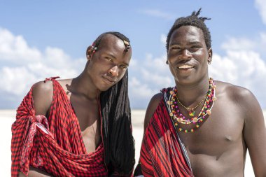 Zanzibar, Tanzanya - 12 Aralık 2019: Geleneksel kıyafetler giymiş iki Afrikalı adam okyanus kenarında, Tanzanya, Doğu Afrika 'daki Zanzibar adasının kumsalında duruyor.