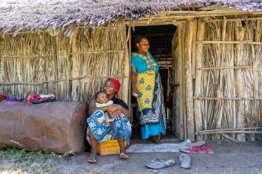 Zanzibar, Tanzanya - 13 Aralık 2019: Doğu Afrika 'da Tanzanya, Zanzibar' da bir sokak üzerindeki saman evin yanındaki Afrikalı aile