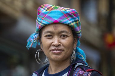 Sapa, Vietnam - Mart 04, 2020: Geleneksel kıyafet ve mücevher giyen etnik Hmong kadını turistlerin Sapa, Kuzey Vietnam 'daki dağ köyünde el sanatları satmalarını bekliyor