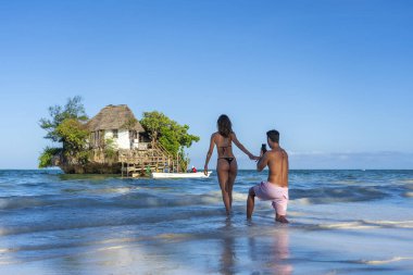Zanzibar, Tanzanya - 11 Ocak 2020: Avrupalı erkek ve kız, Zanzibar adası, Tanzanya, Doğu Afrika 'daki yüksek gelgitte Rock restoranının arka planına karşı fotoğraf çekiliyor.