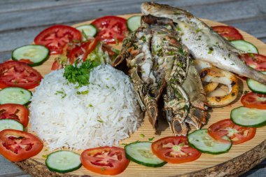 Deniz ürünleri ve sebzeli beyaz pirinç, yakın çekim. Doğu Afrika 'nın Zanzibar adasındaki restoranda balık, mürekkep balığı, karides, pirinç, domates ve salatalık.