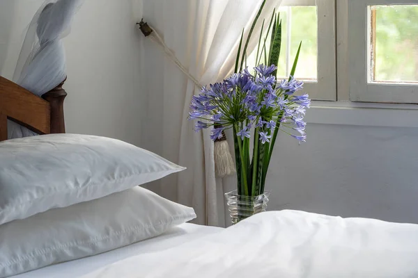 Comfortable soft bed in room and a bouquet of flowers near the window, Tanzania, East Africa, close up