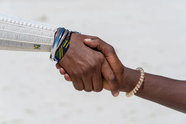 Tribal masai men making handshake in the tropical beach on island Zanzibar, Tanzania, East Africa, close up