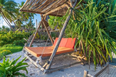 Deniz kenarındaki tropikal plajda, Zanzibar adasında, Tanzanya 'da, Doğu Afrika' da, seyahat ve tatil konseptinde, bir şiltenin altında tahta salıncak.