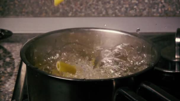 Slow motion curly pasta are falling in a pot of water — Stock Video