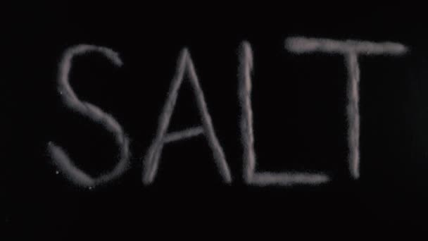 Zeitlupe Wort Salz auf schwarzem Hintergrund geschrieben — Stockvideo
