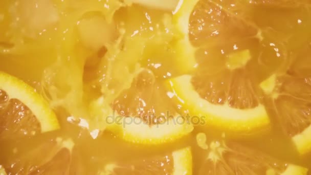Cámara lenta en zumo de naranja con una cuarta parte de caída de hielo vista superior — Vídeos de Stock